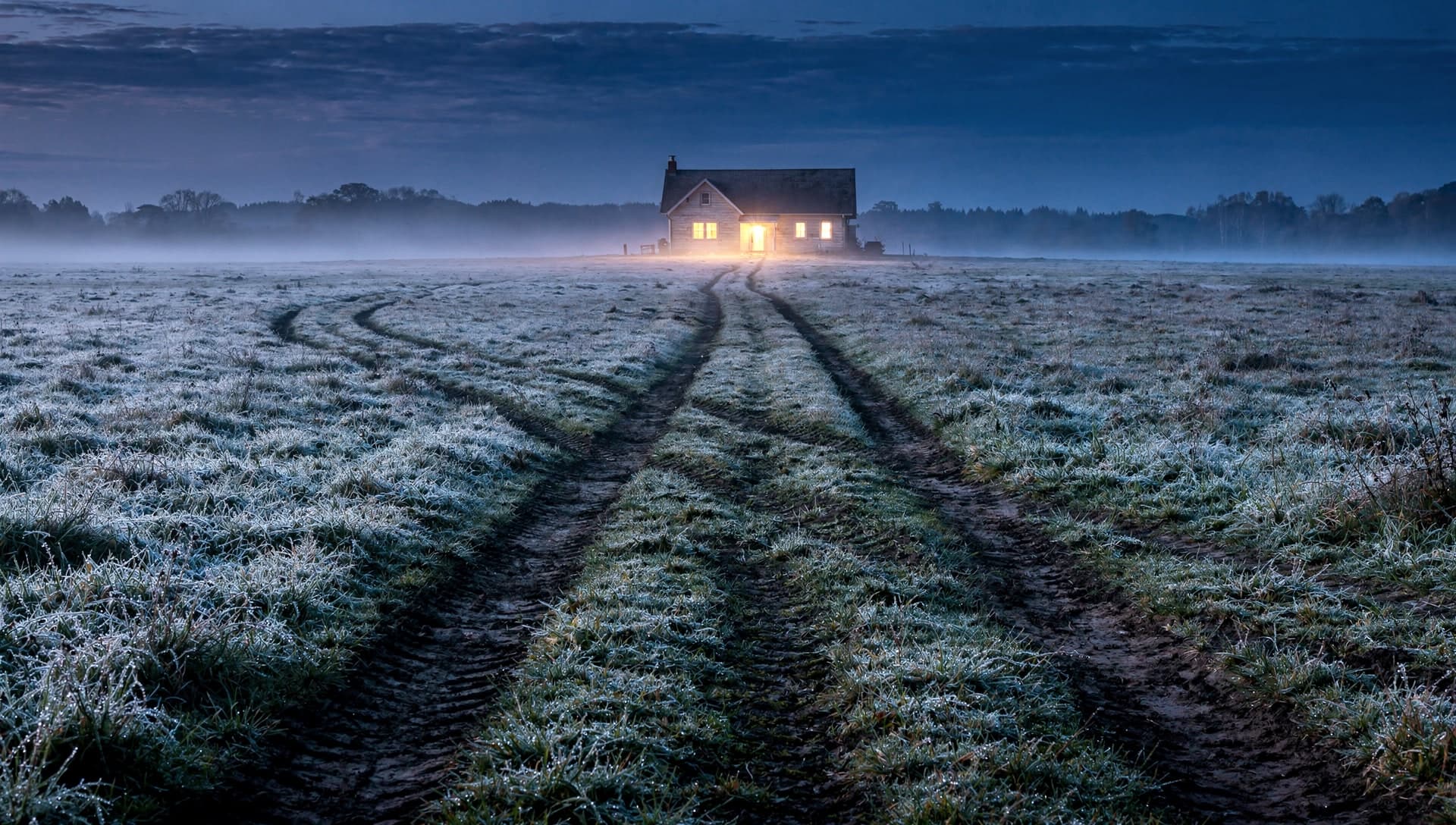 Several worn dirt tracks cross a frosty misty field at blue hour, each arriving from a different direction toward one small farmhouse with warm lit windows glowing in the distance.