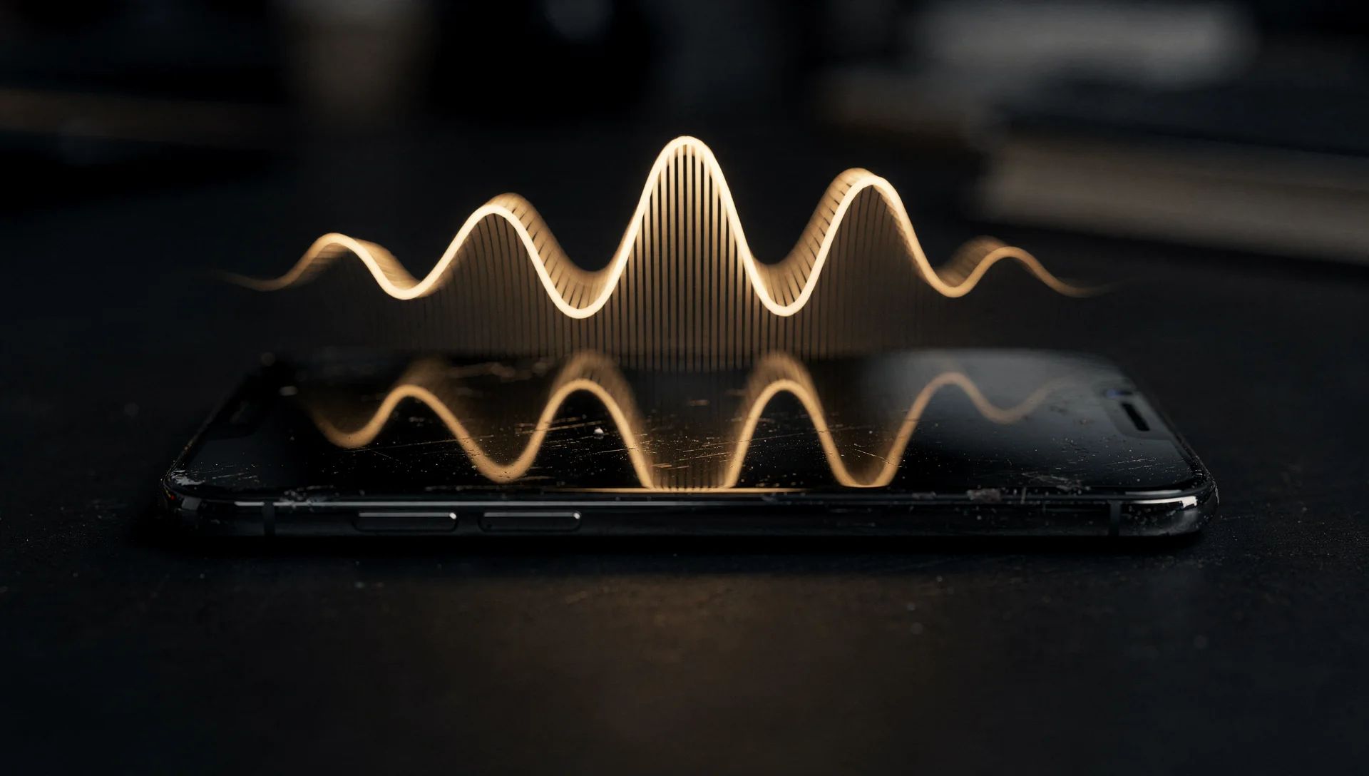 A gold 3D waveform hovering above a phone lying flat on a dark desk