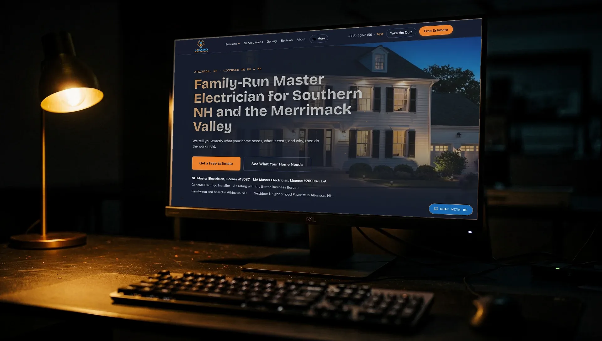 A monitor on a dark desk showing the live homepage of Lembo Electric, an Optimus client site, beside a brass lamp